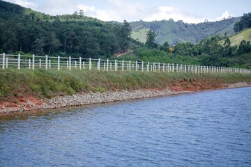 Um portal para entrada da represa para pescadores com lateral para aguas cristalinas e fundo da montanhas.