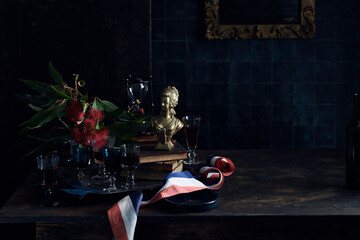 A Bastille Day celebration, tray of glasses with red wine, traditional old master painting and a red white and blue ribbon, colours of the French flag. . 