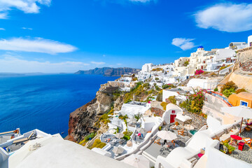 Naklejka premium The steep cliffs of the caldera, the Aegean Sea and the whitewashed village of Oia with the Blue Dome Church in view on the island of Santorini Greece