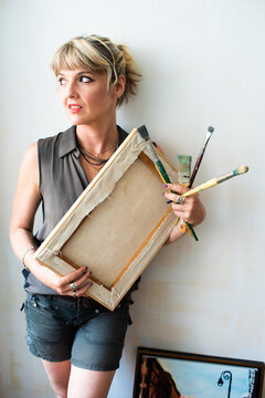 Portrait of fine art painter with painting and paint brushes