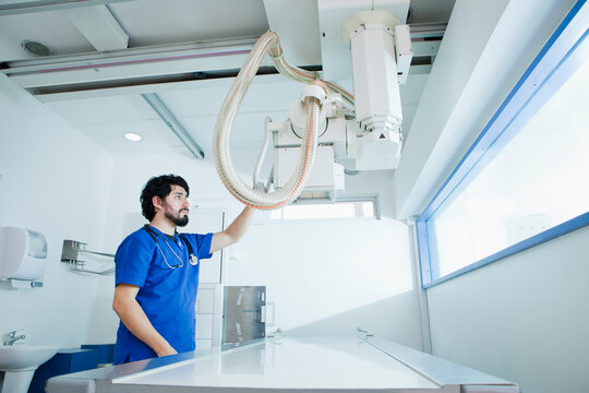 Young male radiographer preparing X-ray machine in radiology department