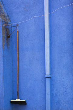 Drain and broom locked with chain on blue stucco exterior house wall, Burano Island, Venetian Lagoon, Venice, Veneto, Italy