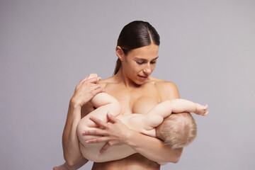 Mother gently calming baby to breastfeed