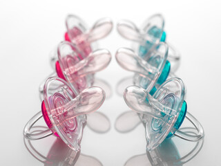 Boy and girl baby soothers in a row, pink and blue, facing off to illustrate gender inequality.