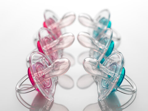 Boy and girl baby soothers in a row, pink and blue, facing off to illustrate gender inequality.