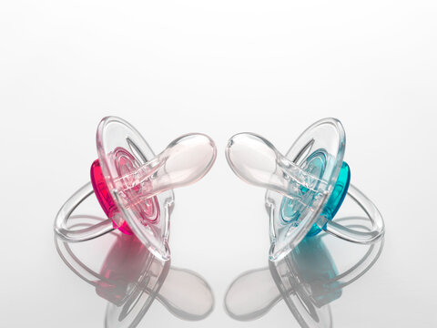 Boy and girl baby soothers, pink and blue, facing off to illustrate gender inequality.