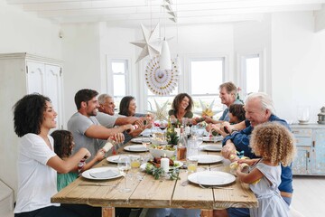 Family popping Christmas crackers together at dining table