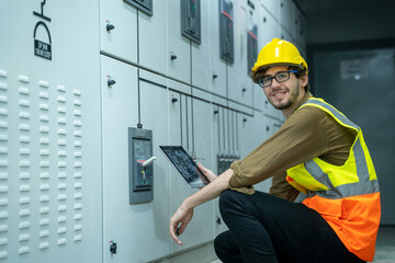 Engineer working on works on a tablet computer in switchgear room of a modern thermal power plant at large industry factory.
