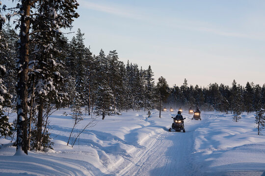Tourists driving snowmobiles in the forest near Jukkasjarvi, Sweden