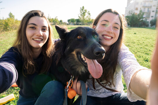 Sisters taking selfie with dog in park
