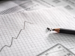 A graph illustrating business data, a line on a chart rising and dipping and a broken lead pencil.