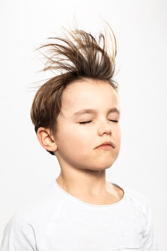 Boy with flying hair closing eyes, white background