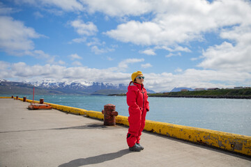 Little girl in snow suit waiting at harbor for boat, Dalvik, Iceland