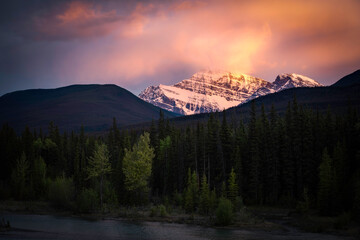 A vivid sunset along the Athabasca River as the clouds above Mount Edith Cavell catch fire in Jasper National Park.