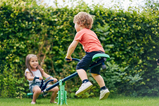 Girl and boy on toy seesaw in garden