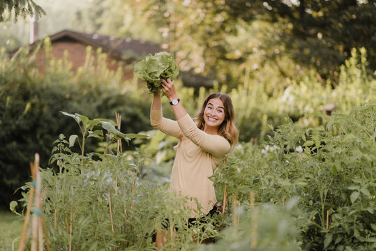  Woman gardener feeling triumphant with lettuce from garden