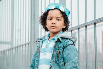 Afro child with urban clothing, with a serious expression. In a courts background. Kids and black people concept.