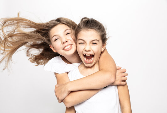 Girl hugging sister from behind, white background