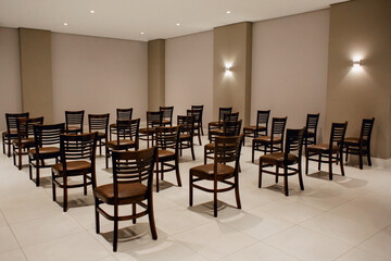 Empty presentation room, lights on, with brown chairs lined up and no person in the room