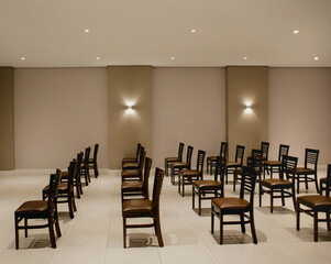 Empty presentation room, lights on, with brown chairs lined up and no person in the room