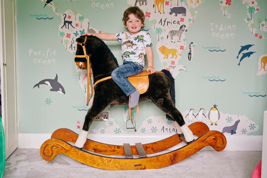 Toddler riding on rocking chair in room