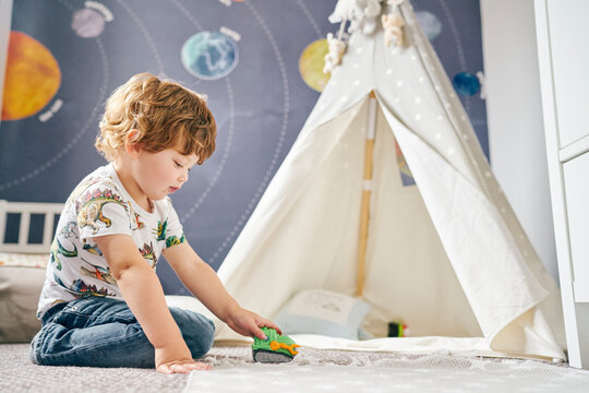 Toddler playing in room, child's teepee, mural of solar system on wall