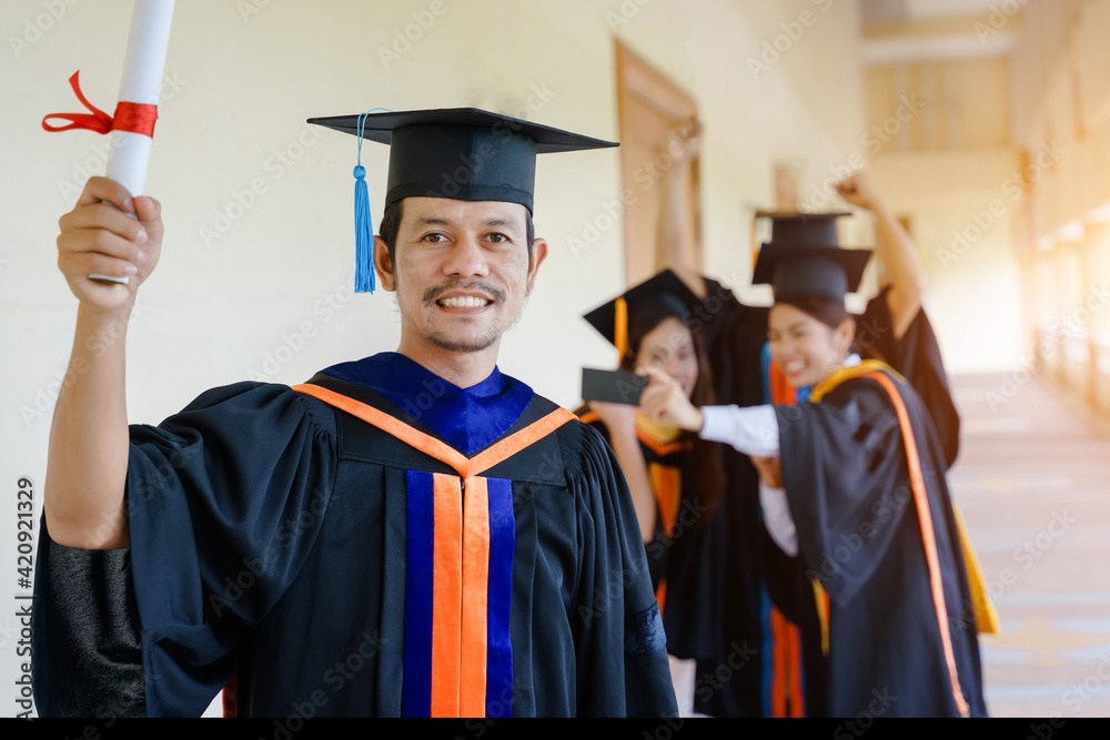 Wall mural the asian university graduates in graduation gown and a mortarboard cap with a degree certificate in