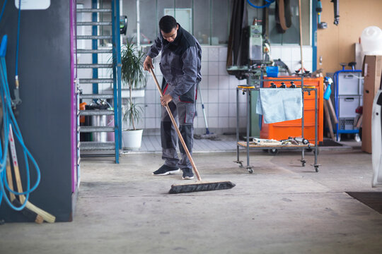 Workman cleaning floor in workshop