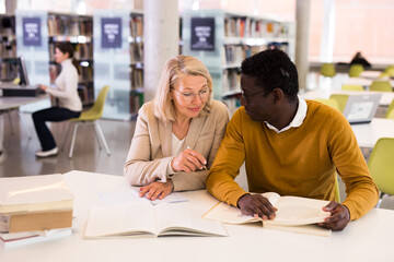 Two adult students studying together in public library. High quality photo