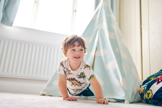 Toddler playing in a teepee in his bedroom at home