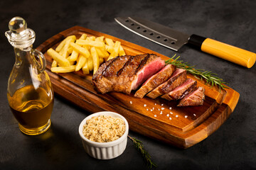 Grilled steak on the cutting board with french fries.