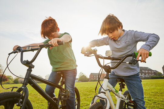 Two boys riding their BMX bikes in a park.