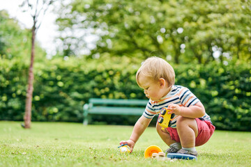 Toddler playing with toy car in park