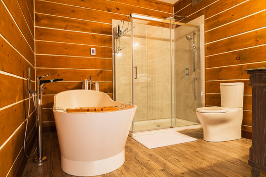 Interior view of bathroom with freestanding tub and wood cladding on walls and floor in a log home
