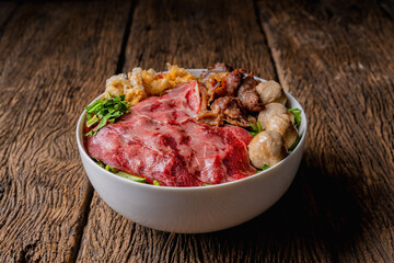 Thai style beef noodle with fresh meat and meatball and stewed beef on wooden table