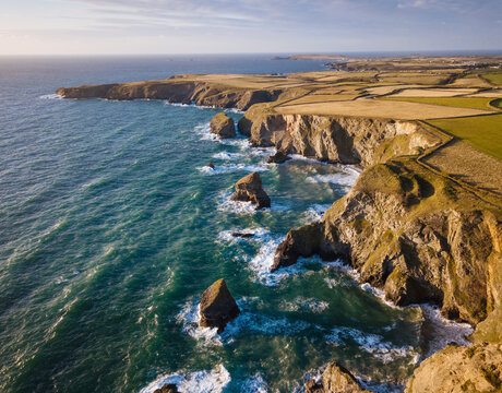 Aerial View of Bedruthan Steps in Cornwall, small secluded beach with steep cliffs and rock stacks offshore. High tide.