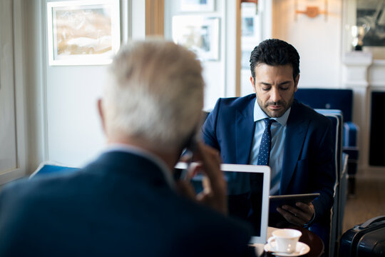 Two businessmen sitting indoors, talking.