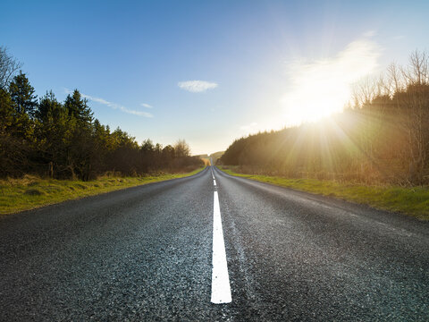 View along straight country road in Ulster, Northern Ireland at sunset.