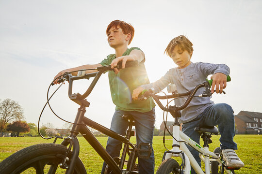 Two boys riding their BMX bikes in a park.