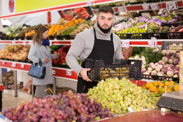 Man seller moving box of bananas in grocery shop. High quality photo