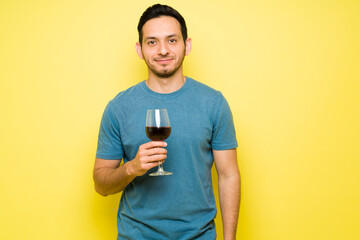 Hispanic young man enjoying a glass of red wine