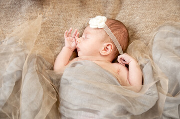 A four week old baby nestled in blankets asleep. 