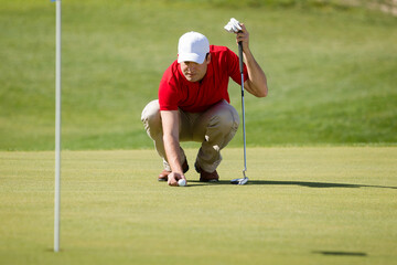 Male golfer putting.
