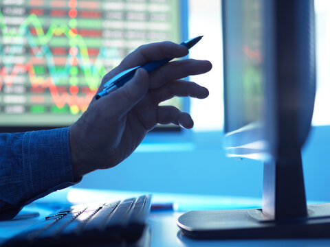 Close up of stock market trader analysing share price data on the screen.