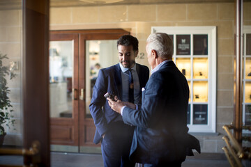 Two businessmen standing in hotel lobby, talking.