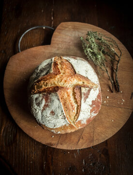 High angle close up of freshly baked sourdough bread on wooden cutting board.
