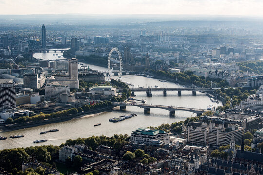 Aerial view of the City of London and the River Thames towards the west, with landmarks like the London Eye, and rooftops. 