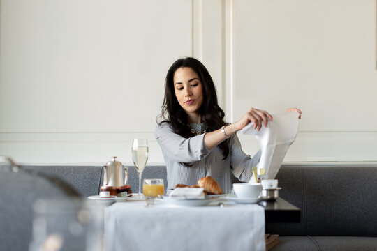 Young woman preparing napkin whilst having champagne breakfast at  boutique hotel in Italy