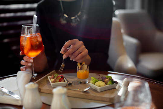 Cropped shot of young woman staying in boutique hotel eating aperitif