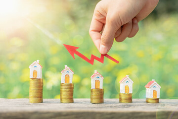 The investor's hand catches the red arrow.Business investment ideas.Concept of real estate investment.Business growth.House on a pile of coins.Stack of coins arranged in ascending order.